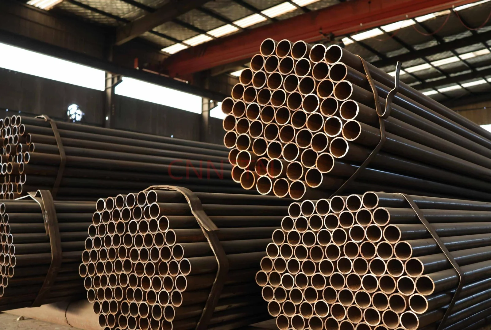 Circular steel tubes stacked in a workshop.